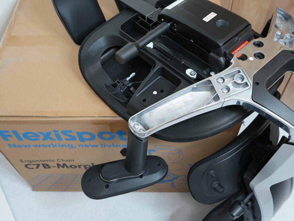 FlexiSpot C7 Morpherを、梱包用の段ボールの上に置いて組み立てている写真2